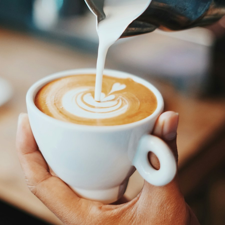 Barista pouring milk into a latte, making a leaf pattern